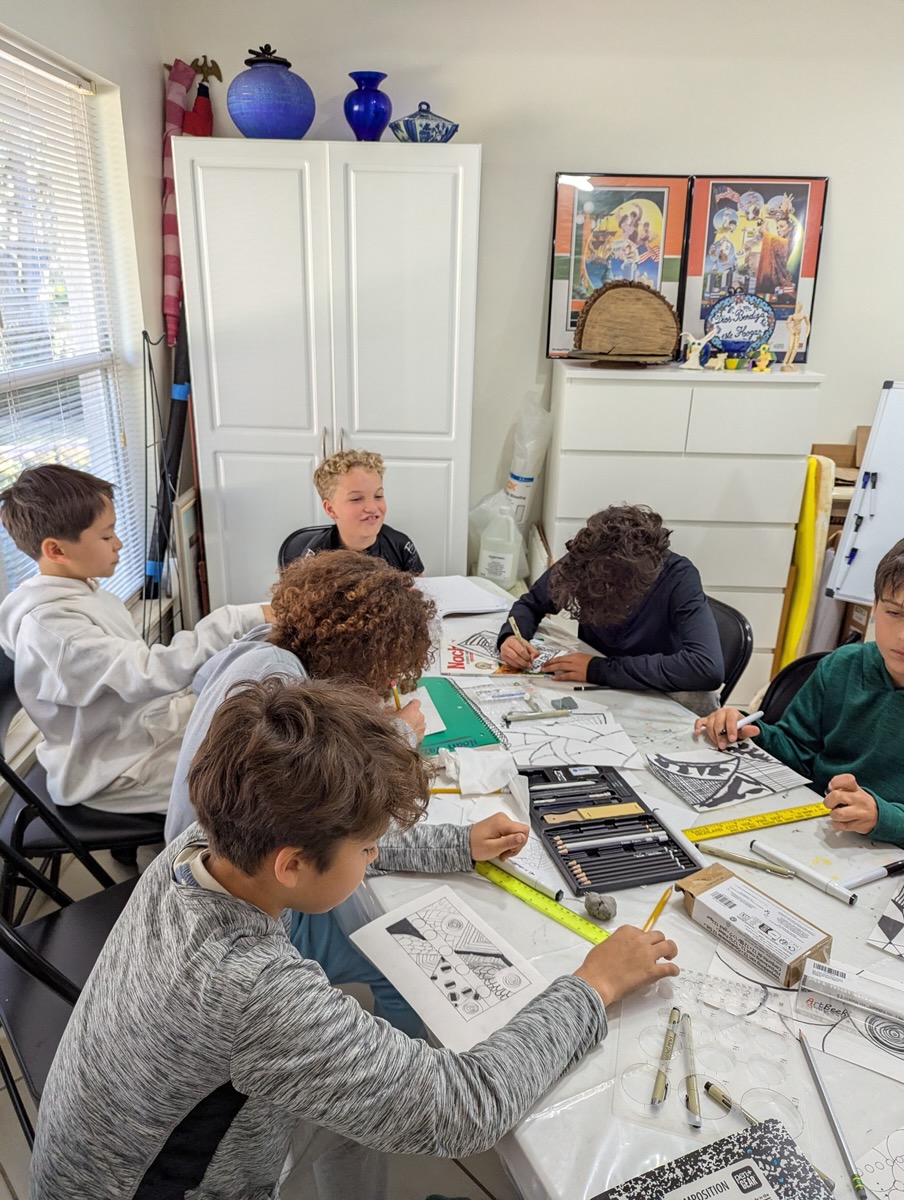 Students drawing together around the studio table during a Monday class